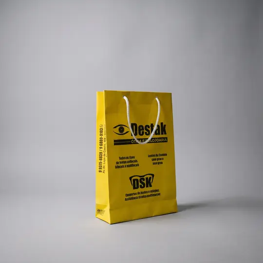 Sacola de papel amarela, estreita, com a logo e informações da loja impressas