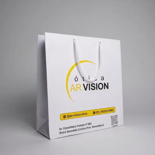 Sacola de papel branca com a logo em amarelo e azul e alça de fita branca