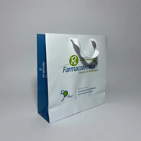 Sacola de papel branca com a lateral azul e alça de fita branca