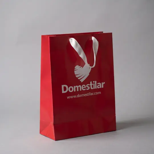 Sacola de papel vermelha com a logo em branco e alça de fita branca